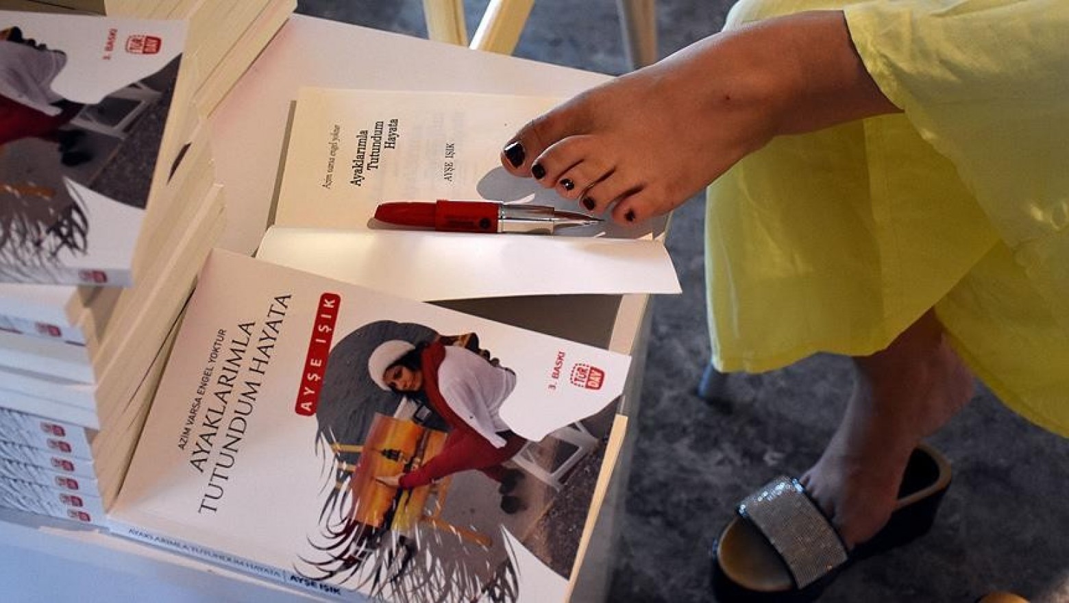 Kitabını ayağıyla imzaladı